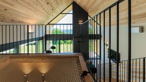 A modern interior with a wooden ceiling, a view of a green landscape, and a netted area. - Blacksmith House - Stylish vacation home with spa & nature views (Varaždinske Toplice)