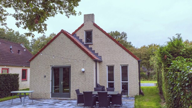 Ein zweistöckiges Haus mit Backsteinfassade, einer Haustür und einem kleinen Fenster.