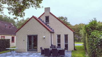 A two-story house with a brick exterior, a front door, and a small window.
