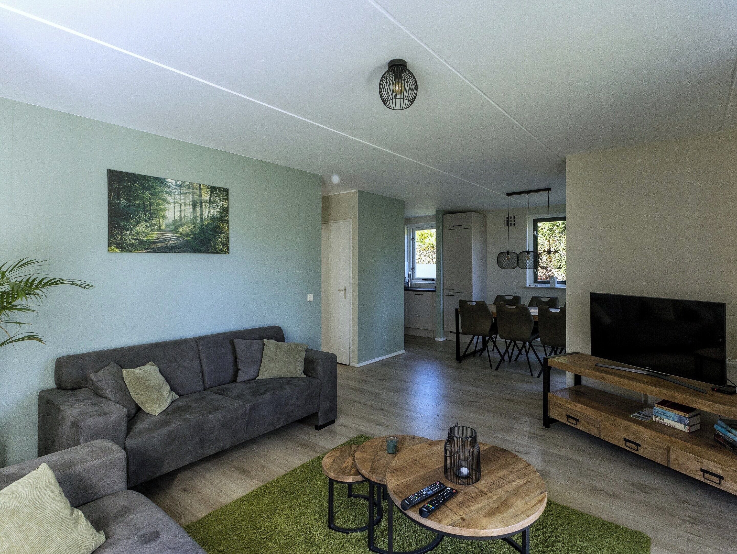 A modern living room with a sofa, coffee table, TV, and a painting on the wall.