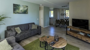 Ein modernes Wohnzimmer mit einer Couch, einem Couchtisch, einem Fernseher und einem Gemälde an der Wand.