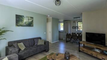 A modern living room with a sofa, coffee table, TV, and a painting on the wall.