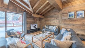 L’intérieur d’un chalet confortable, avec un canapé, des fauteuils, une table basse et un téléviseur.