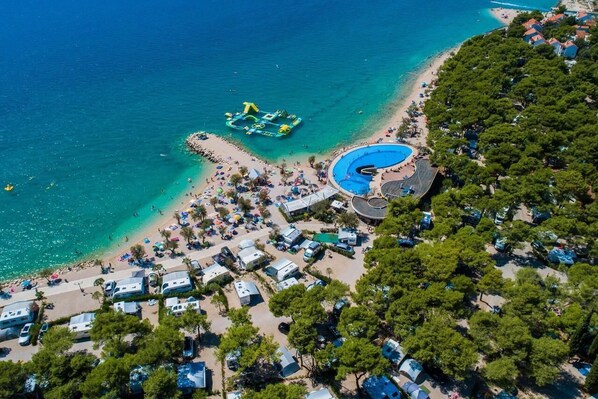 Ett flygbildsfoto av ett semesterområde vid stranden med plats för husbilar, en swimmingpool och en vattenpark.