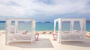 Two white lounge chairs with red accents, positioned on a sandy beach with a view of the sea and distant islands. - Amadria Park Sibenik Apartment 4+3 for 7 persons (Sibenik)