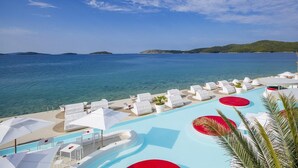 A resort pool area with lounge chairs and umbrellas, overlooking a clear blue sea and distant islands. - Amadria Park Sibenik Beach Villa for 7 persons (Sibenik)