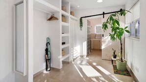 A hallway with a white door, a hanging plant, a rack with baskets, and a potted plant. - Holiday Home 'Casa A'Venda' with Mountain View, Wi-Fi and Air Conditioning (Moncarapacho)
