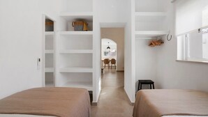 A hotel room with two beds, a wardrobe, a desk with chairs, and a view of the street. - Holiday Home 'Casa A'Venda' with Mountain View, Wi-Fi and Air Conditioning (Moncarapacho)