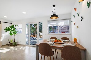 A dining area with a table set for four, a potted plant, and a view of the outdoors. - Holiday Home 'Casa A'Venda' with Mountain View, Wi-Fi and Air Conditioning (Moncarapacho)