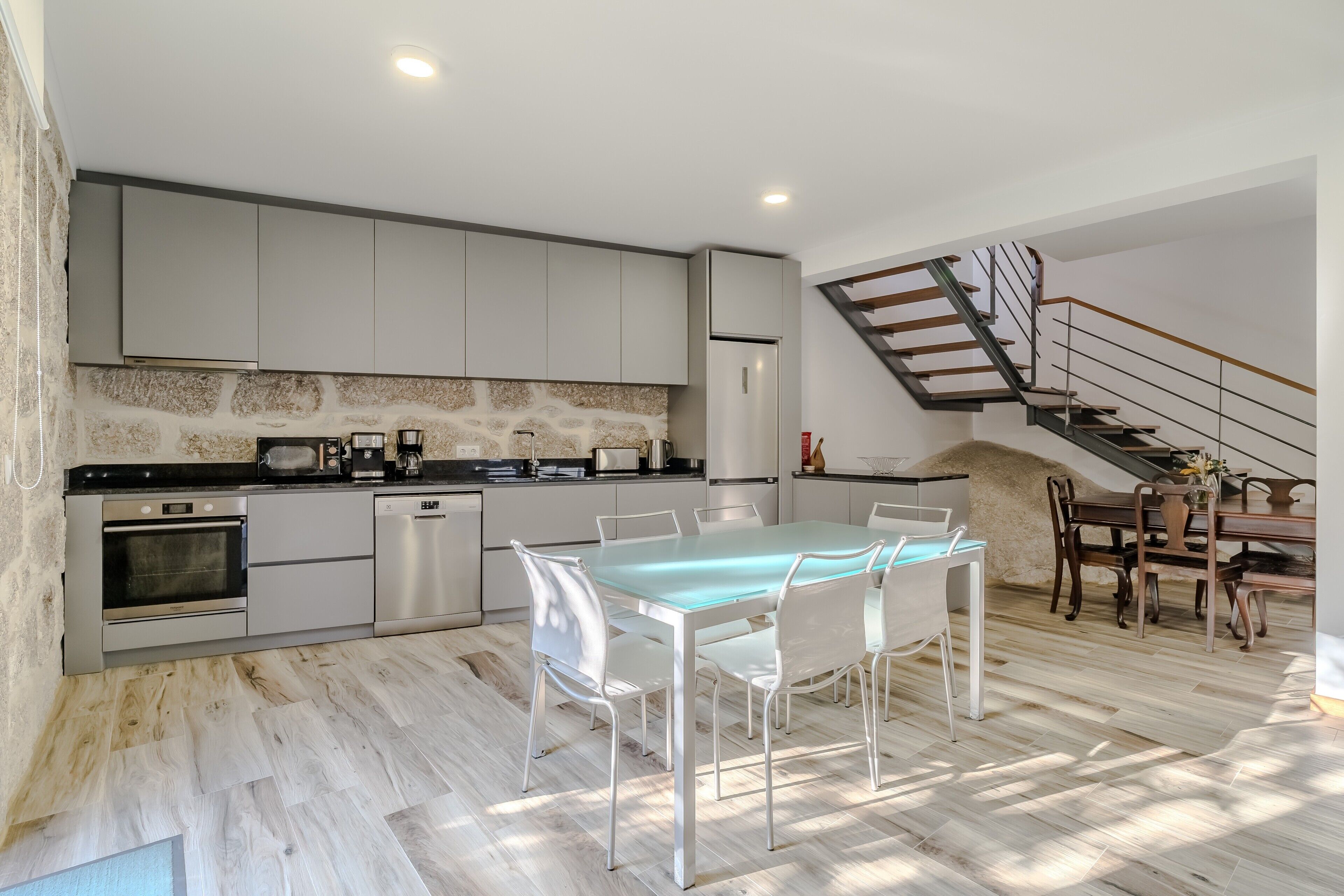 Una cocina moderna con comedor, horno empotrado, lavavajillas y refrigerador.