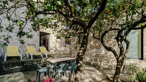 A stone building with a courtyard, outdoor seating, and a tree. - Holiday Home 'Casa Feixa Gerês' with Mountain View, Wi-Fi & Air Conditioning (Gerês)