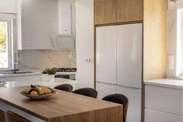 A modern kitchen with white cabinets, a wooden countertop, a built-in oven, and a refrigerator. - Luna Mare in Agia Marina Chrysochous (Ayia Marina Chrysochous)