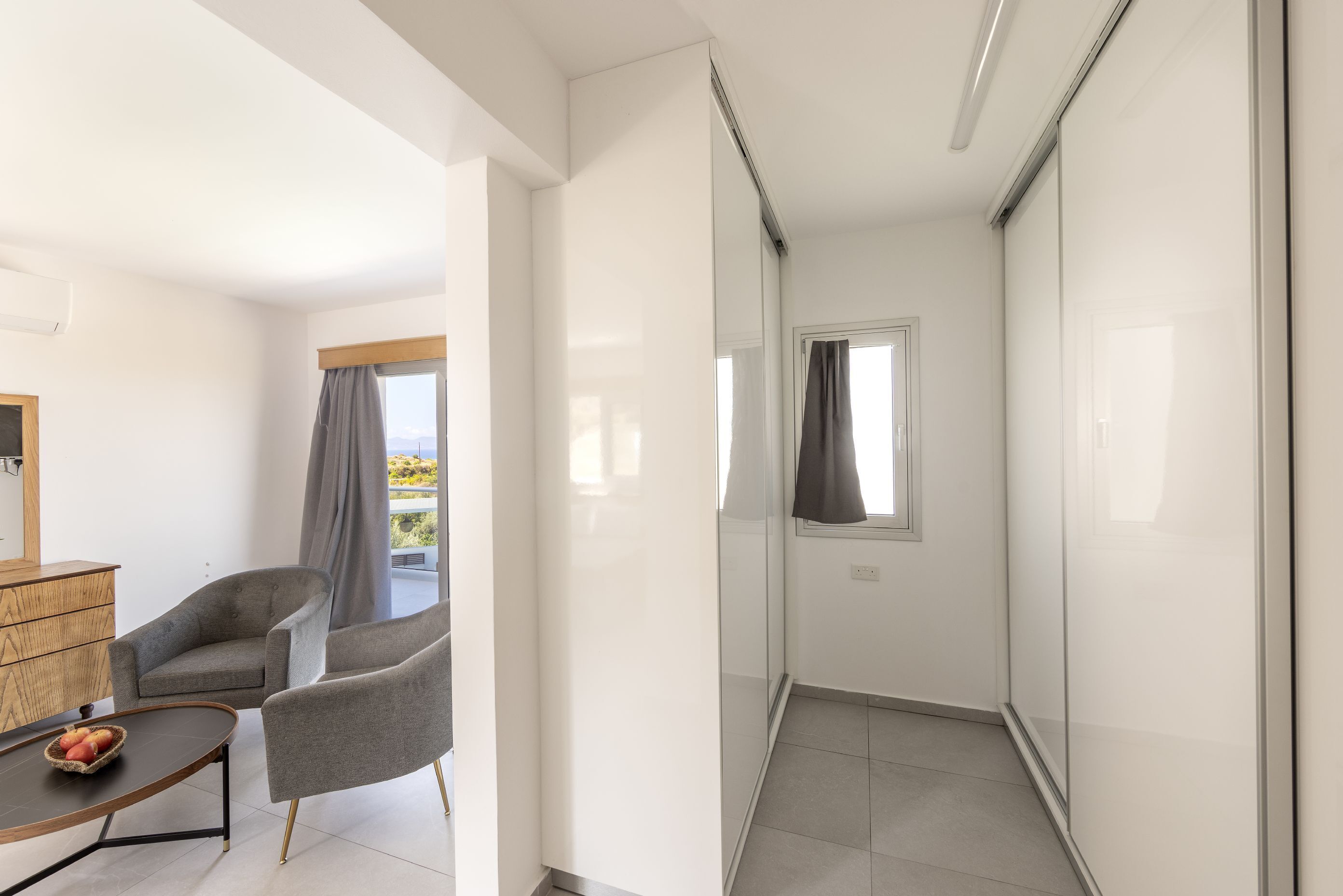 A modern room with a sofa, a small table, and a view of a balcony.