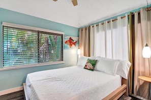A bedroom with a bed, a window with blinds, a painting, and a curtain rod.
