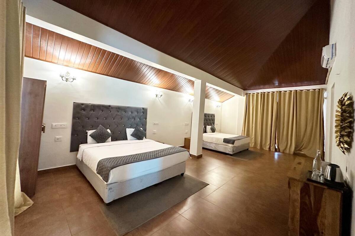 Een slaapkamer met een groot bed, een kleiner bed en een slaapbank. Er is een houten plafond en een kroonluchter.