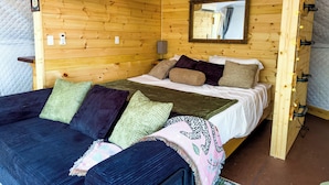 Une pièce chaleureuse en bois, avec un lit superposé, une table de chevet, un miroir et des guirlandes lumineuses.