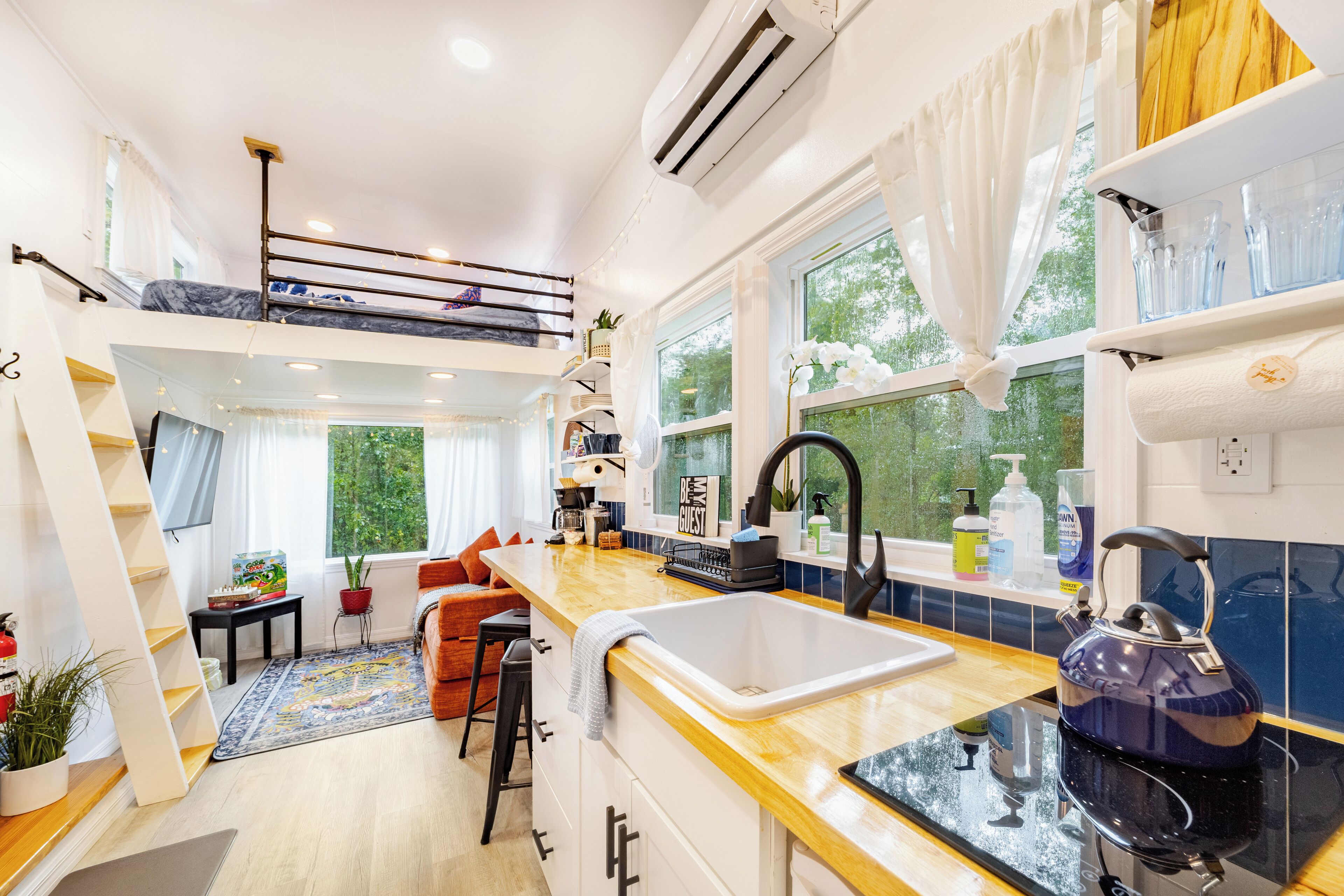 A compact kitchen with a wooden countertop, a sink, and a kettle. There is a small dining area with a table and chairs.