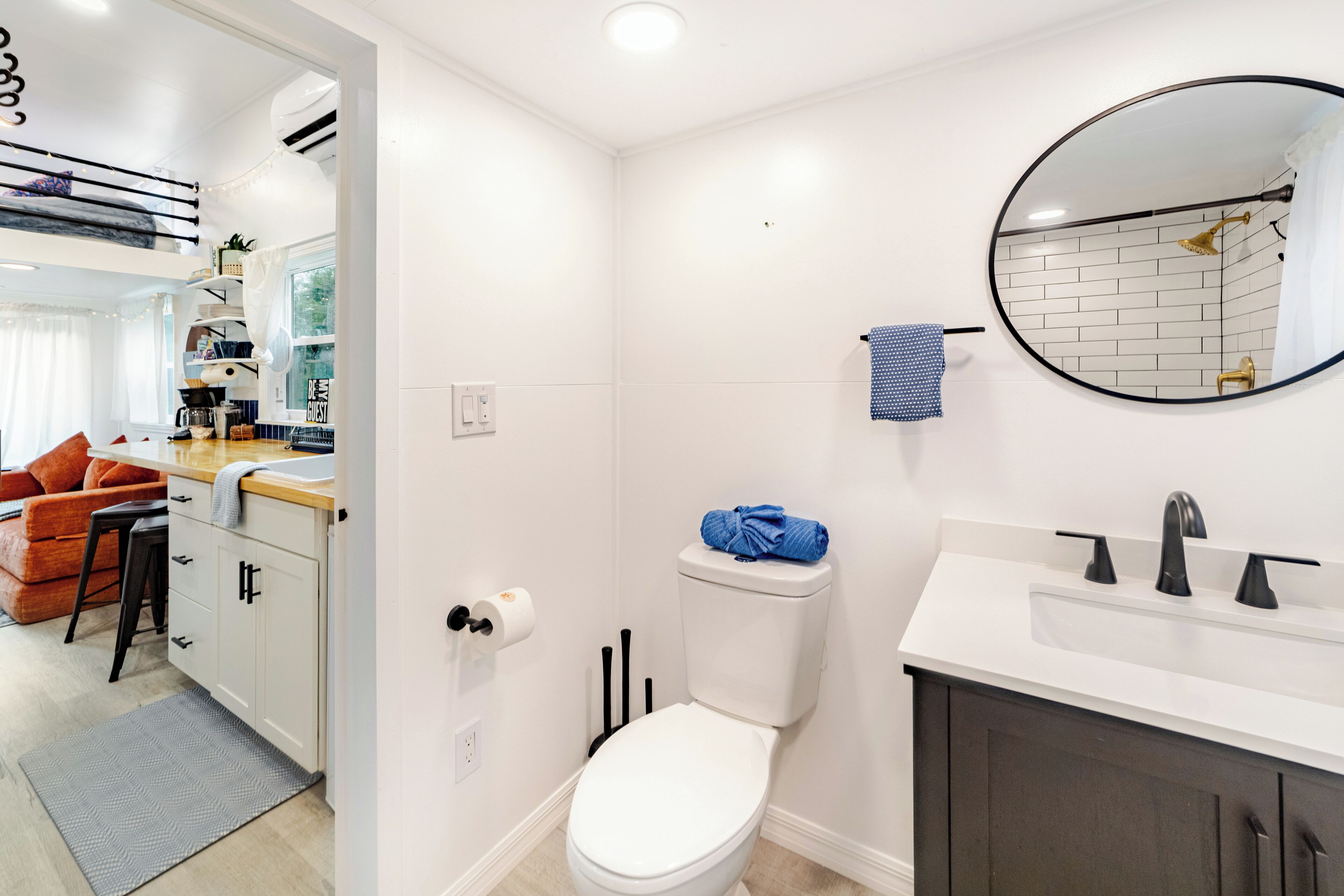 Une salle de bain moderne avec des toilettes blanches, un lavabo avec un miroir et une serviette accrochée au mur.