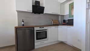 Een compacte keuken met een vaatwasser, oven en koffiezetapparaat op het aanrecht.