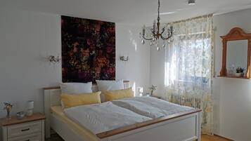Ein Schlafzimmer mit einem großen Bett, einer Kandelaber, floralen Vorhängen und einem Wandteppich mit Blumenmuster.