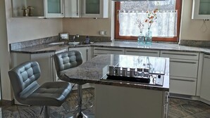 A modern kitchen with a central island, bar stools, and a window with a view. - Vacation apartment "Fröhlich am Baderbichl" (Tutzing)