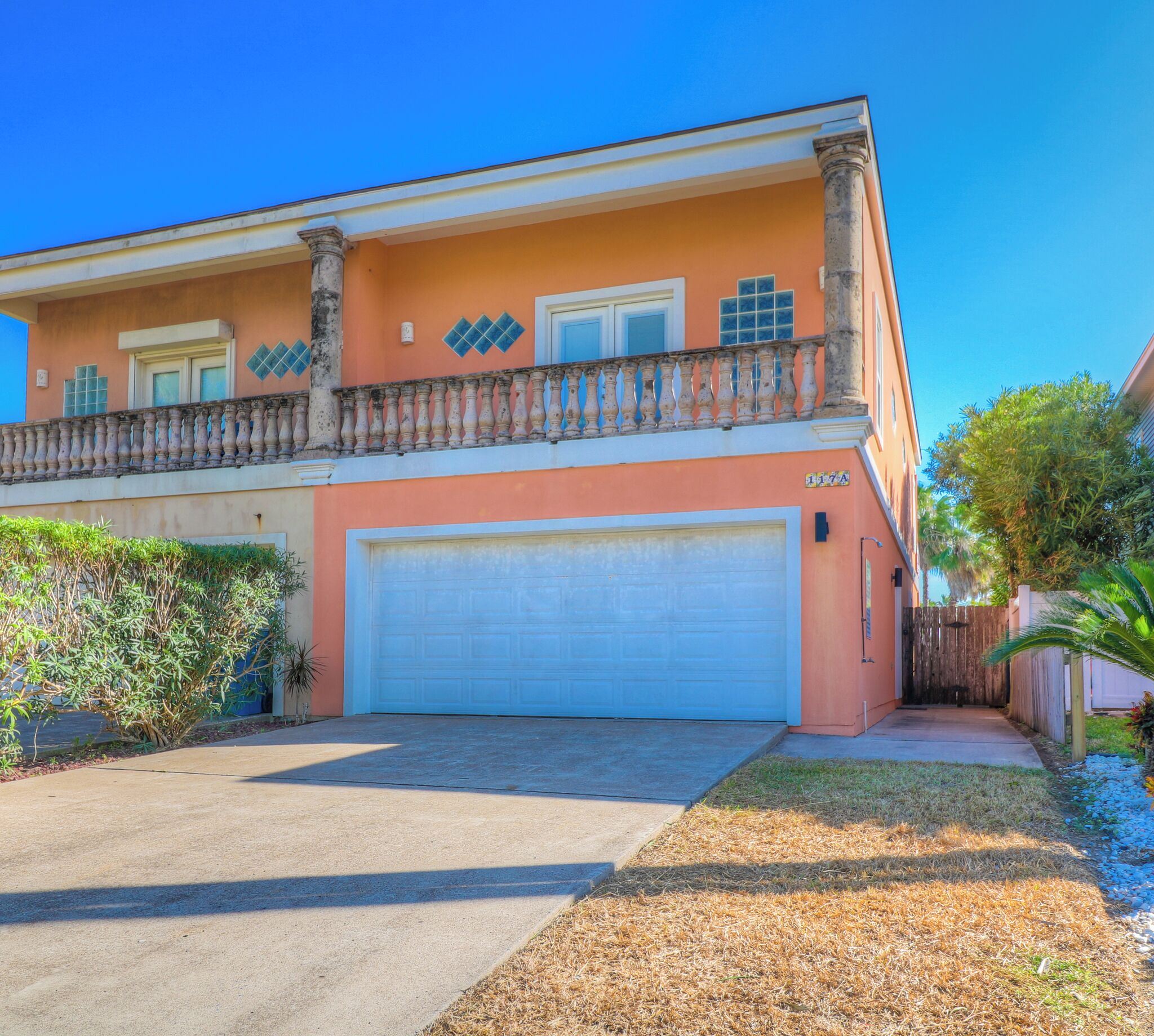 A two-story house with a garage, a balcony with a balustrade, and a well-maintained lawn.