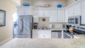 A modern kitchen with white cabinetry, stainless steel appliances, and decorative fish on the wall.