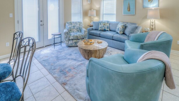 A living room with a blue sofa, a patterned armchair, a round coffee table, and a metal chair.