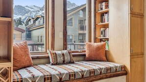 A cozy room with a built-in bench by a large window overlooking a snowy mountain.