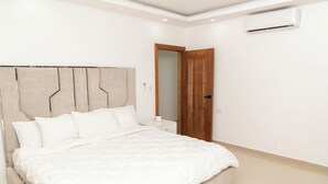 A bedroom with a large bed, a wooden door, and an air conditioning unit on the wall. - La Isla Royal-Sistema Solar, a lovely 3 bed Penthouse apartment in Miches, DR (Miches)