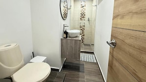 Une petite salle de bain comprenant des toilettes, un lavabo et un espace douche.