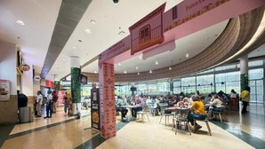 Un espace intérieur spacieux, aménagé avec des tables et des chaises pour les repas, de grandes fenêtres laissant entrer la lumière naturelle et un plafond aux lignes courbes.