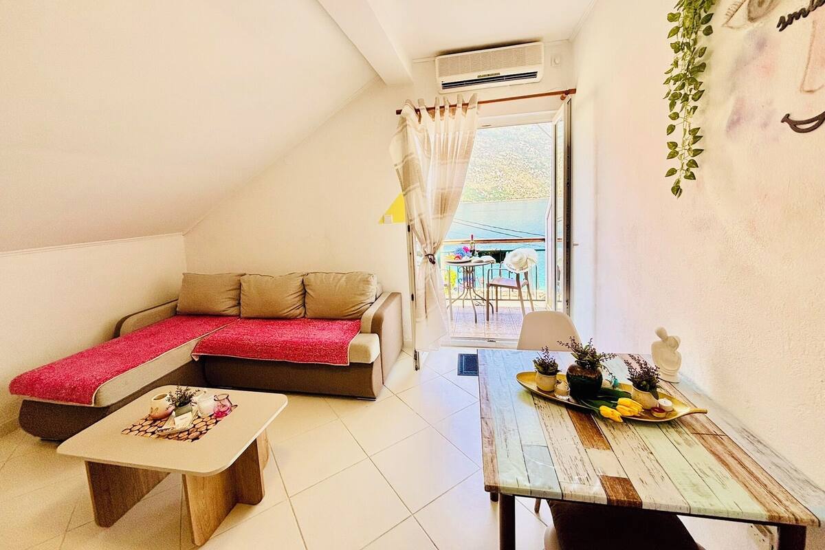 A cozy room with a sofa, a small table, and a dining table with a plant and a tray of fruit.