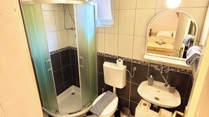 Ein Badezimmer mit Duschkabine, Toilette, Waschbecken und Spiegel.