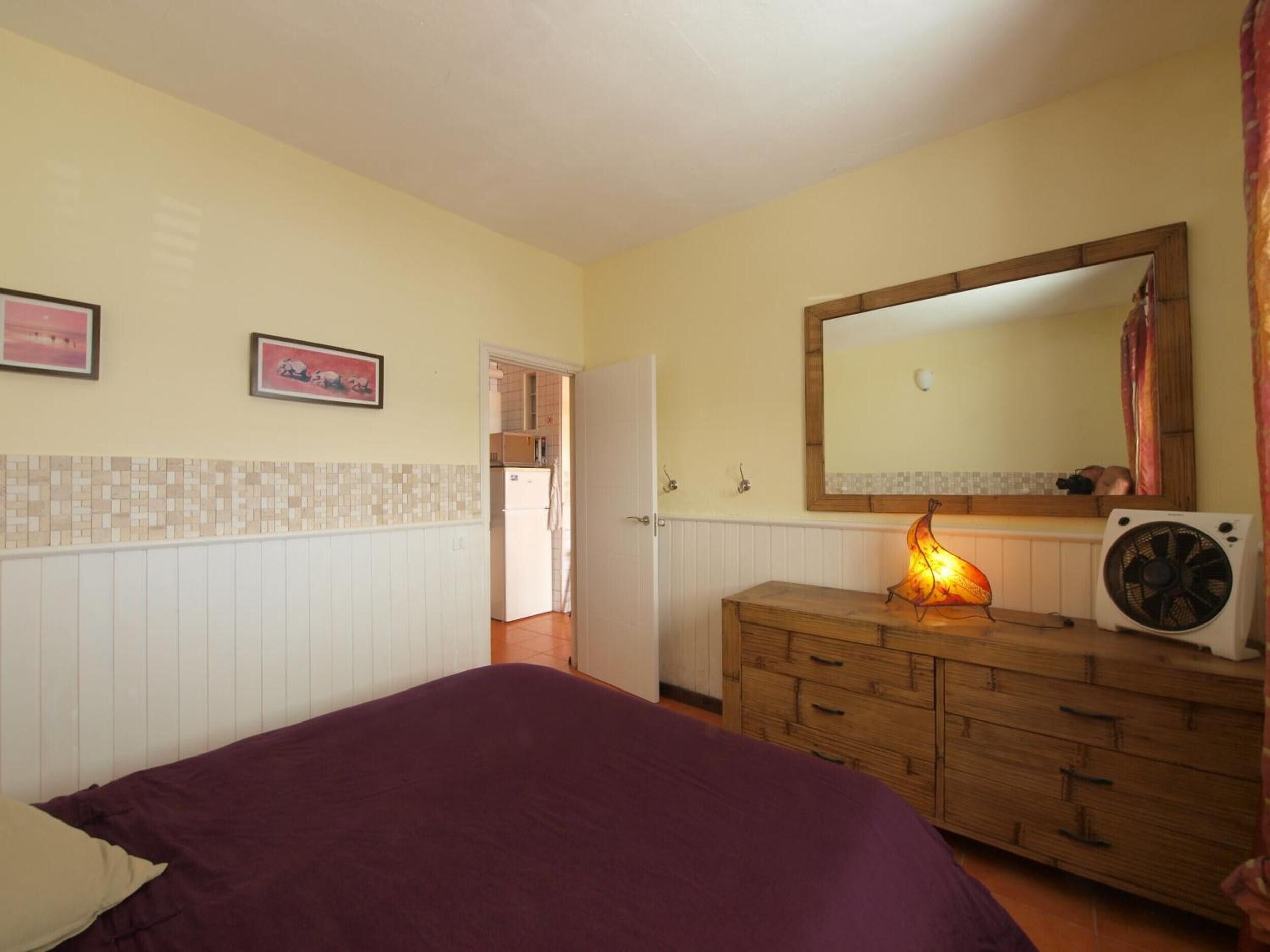 A bedroom with a bed, dresser, mirror, and a door leading to a bathroom.