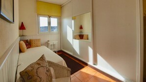A bedroom with a bed, bedside table, lamp, window, and a mirror. - Vacation Home 'Sunrise Directly by the Sea' with Sea View, Private Terrace and Wi-Fi (La Mareta)