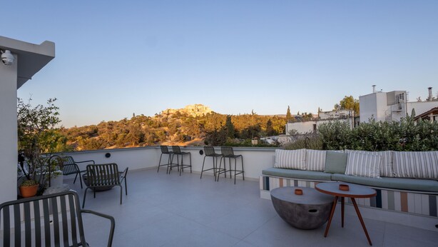 A rooftop terrace with seating, a view of a hilltop structure, and surrounding vegetation. - Best view of Acropolis - Modern 2BR Apt by Meros (Athina)