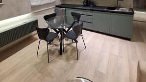 A modern kitchen with a dining area, featuring a glass table, black chairs, and a built-in island with a sink. - Charming 1-bedroom apartment in the heart of welcoming Agia Napa with AC (Ayia Napa)