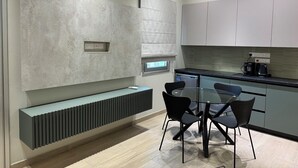 A modern kitchen with a built-in dishwasher, a dining table with chairs, and a built-in bench. - Charming 1-bedroom apartment in the heart of welcoming Agia Napa with AC (Ayia Napa)