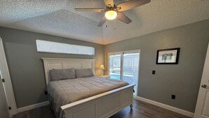 A bedroom with a bed, ceiling fan, window, and a door. - Peaceful Lake Berkley Retreat (Kissimmee)