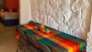 Une table à manger avec une nappe colorée, un vase et un saladier.