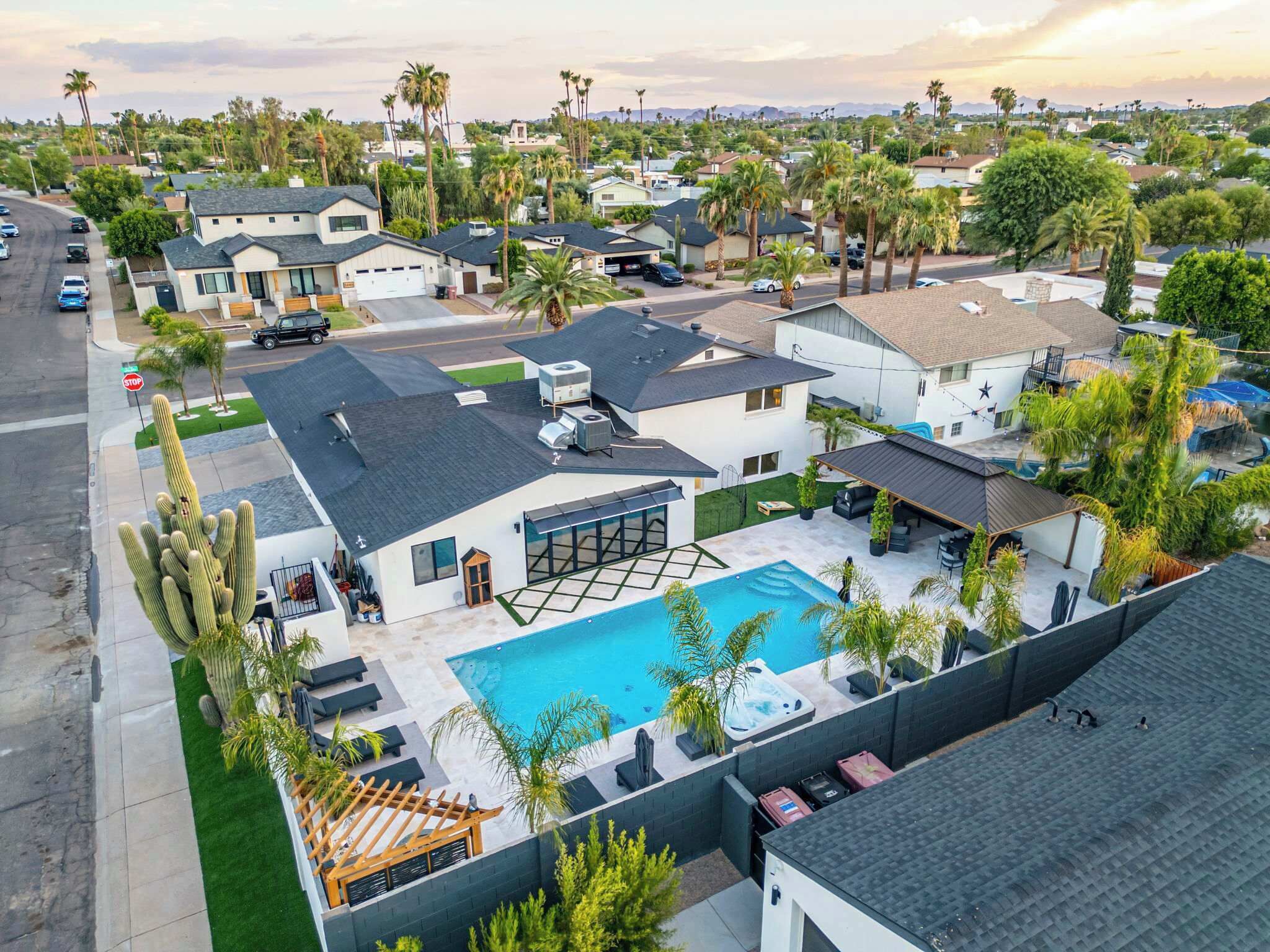 A residential area with a swimming pool, houses, and palm trees.