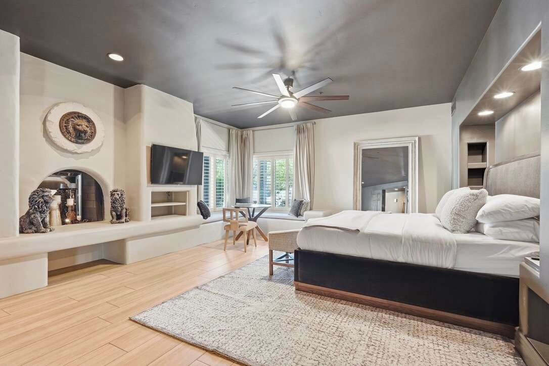 Une chambre à coucher moderne, équipée d’un lit, d’un ventilateur de plafond, d’une cheminée et d’un téléviseur.