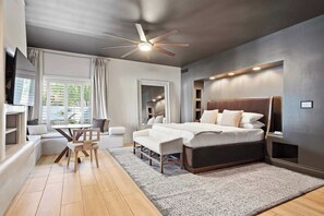 A modern bedroom with a large bed, a ceiling fan, and a seating area with a table and chairs.