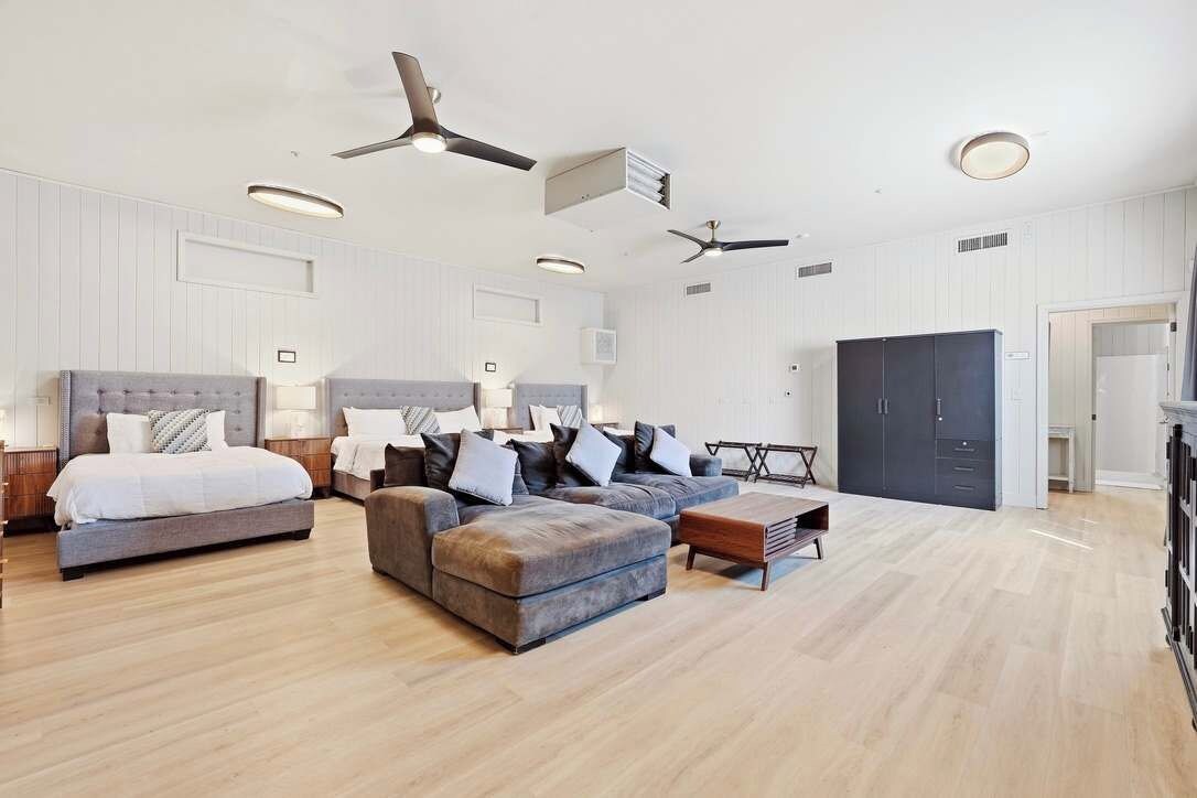 A spacious bedroom with a large bed, a sofa, a coffee table, and a wardrobe.