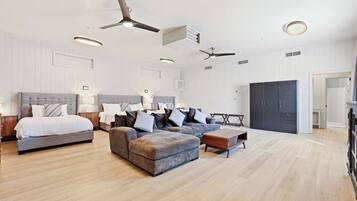 A spacious bedroom with a large bed, a sofa, a coffee table, and a wardrobe.