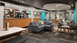 A modern hotel lobby with a bar, seating area, and a reception desk. - Holiday Inn NORTHAMPTON by IHG (Northampton)