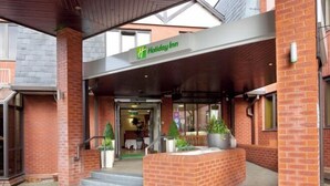 A Holiday Inn entrance with a covered walkway, brick facade, and potted plants. - Holiday Inn NORTHAMPTON by IHG (Northampton)