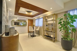 A modern living room with a dining area, a large potted plant, and a decorative shelf unit. - Acqualina s View @ Santo Domingo (Santo Domingo)