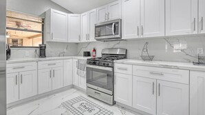 Una cocina moderna con gabinetes blancos, estufa de acero inoxidable y microondas.